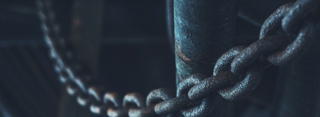 Close up of metal chain hung across a pillar in a dark room